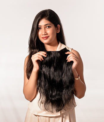 Person with long, straight hair extensions on a plain background