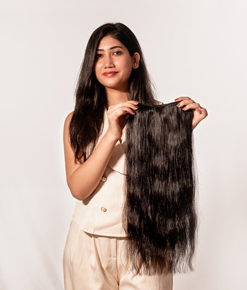 Person with long, straight hair extensions on a plain background
