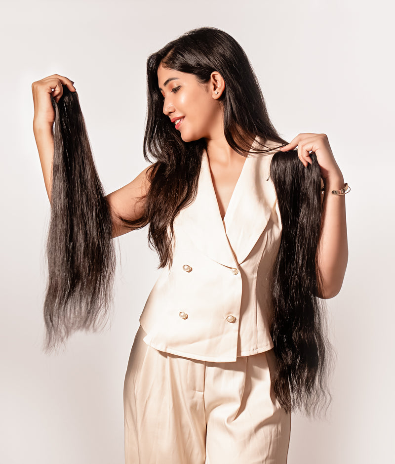 Woman holding long hair extensions against a white background