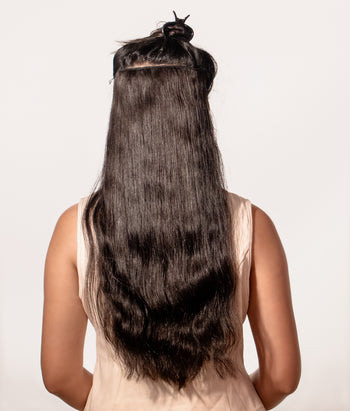 Person with long, straight hair extensions on a plain background
