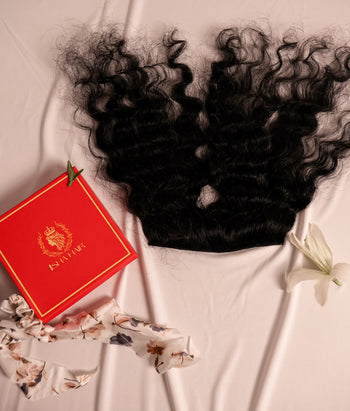 Curly hair extensions with a red box featuring a logo on a light fabric background