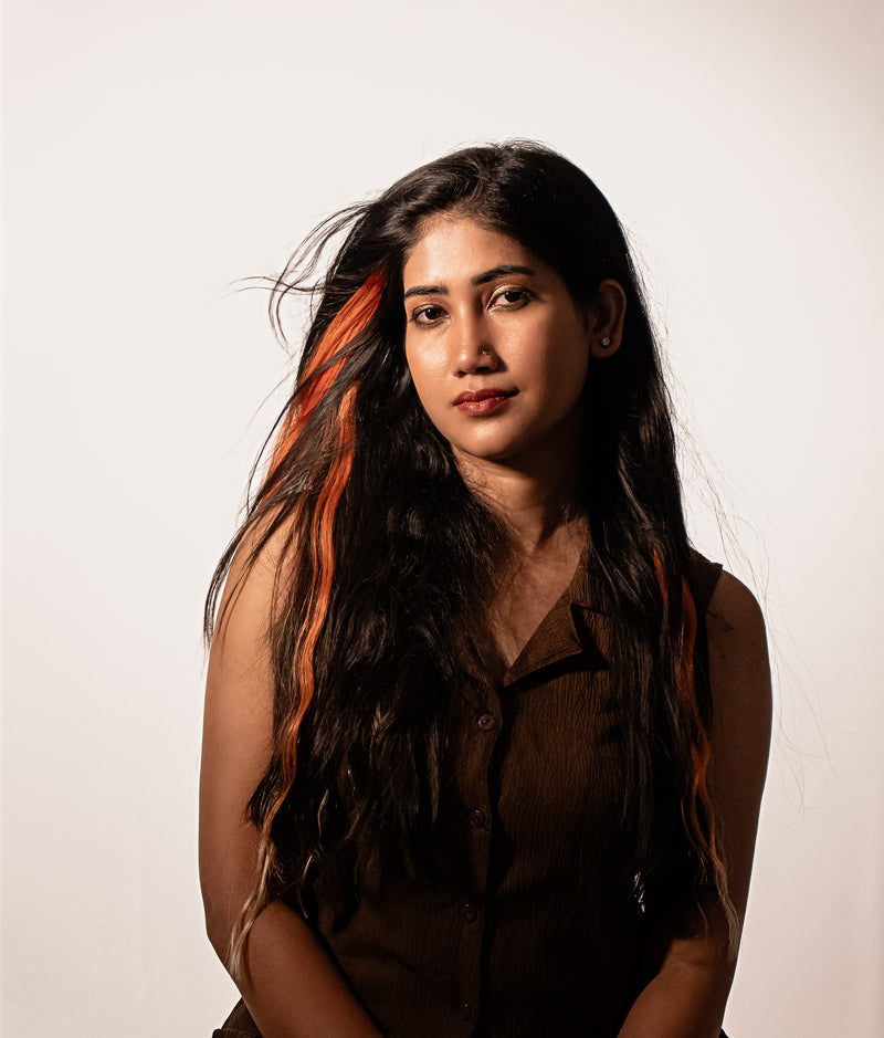 Woman with long dark hair and orange highlights using Color Shade Clip Hair Extensions against a white background.